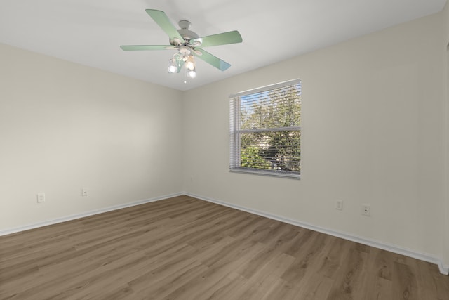 empty room featuring ceiling fan, baseboards, and wood finished floors