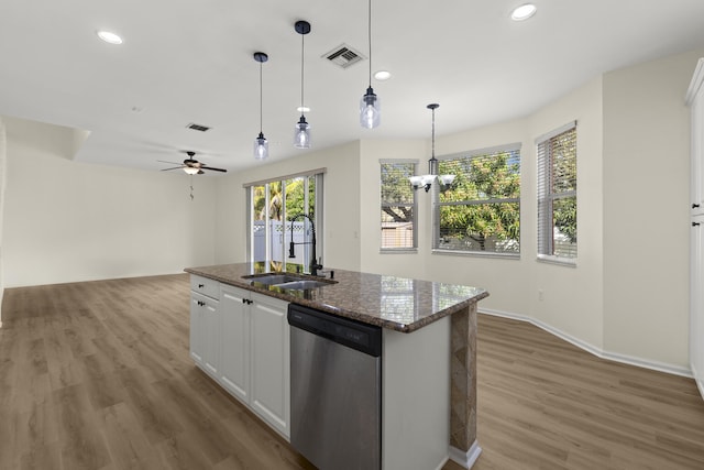 kitchen with a sink, visible vents, white cabinetry, stainless steel dishwasher, and a center island with sink