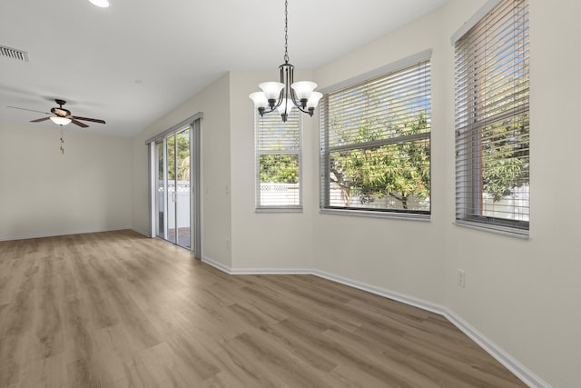 unfurnished dining area with visible vents, baseboards, wood finished floors, and ceiling fan with notable chandelier