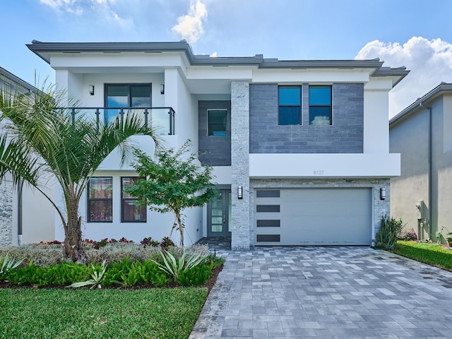 view of front of home with a garage, decorative driveway, a balcony, and stucco siding