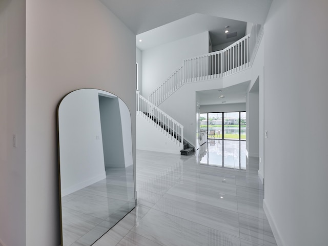 interior space with arched walkways, recessed lighting, a high ceiling, baseboards, and stairway