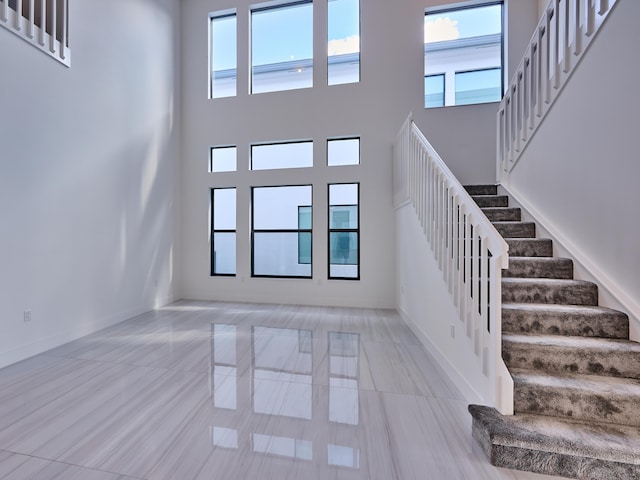 interior space featuring stairs, a high ceiling, tile patterned floors, and baseboards