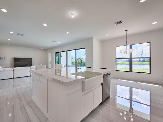 kitchen featuring a center island with sink, visible vents, stainless steel dishwasher, open floor plan, and a sink