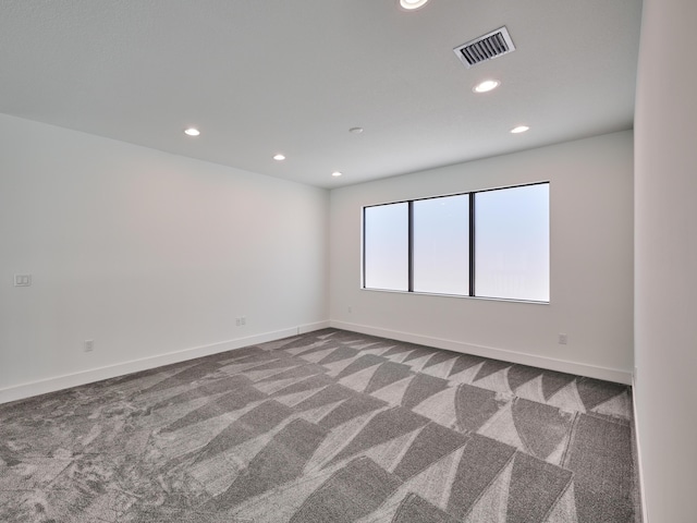 carpeted spare room featuring baseboards, visible vents, and recessed lighting