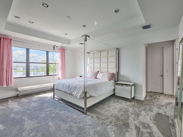 carpeted bedroom with a raised ceiling, visible vents, a textured ceiling, and baseboards