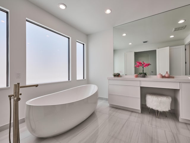 full bath with recessed lighting, vanity, baseboards, visible vents, and a soaking tub