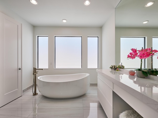 full bath featuring a soaking tub, vanity, and recessed lighting