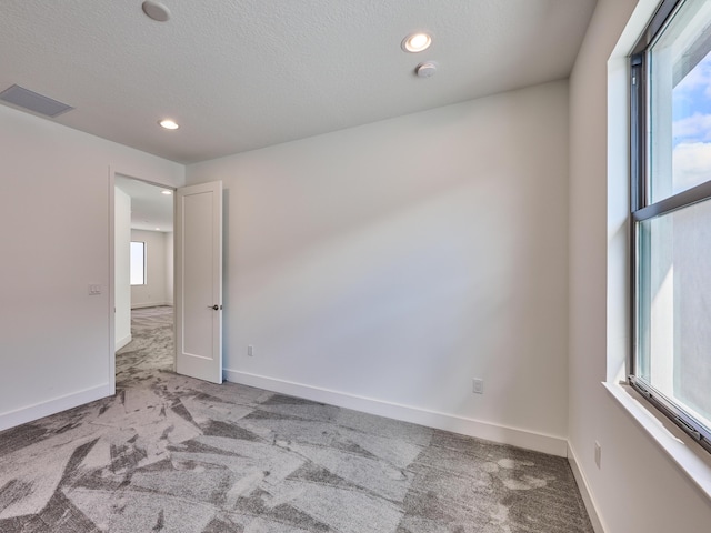 spare room featuring carpet floors, baseboards, and visible vents