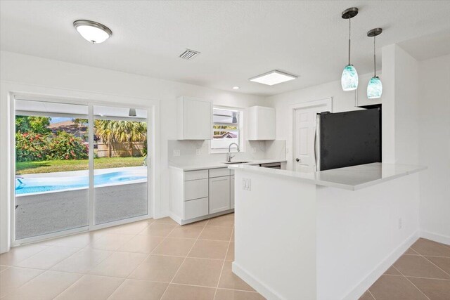 kitchen with visible vents, appliances with stainless steel finishes, a peninsula, white cabinets, and light tile patterned floors