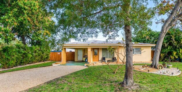 ranch-style home featuring a front yard, fence, driveway, and stucco siding