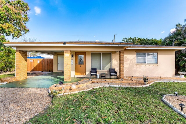 ranch-style home with aphalt driveway, fence, a front lawn, a carport, and stucco siding