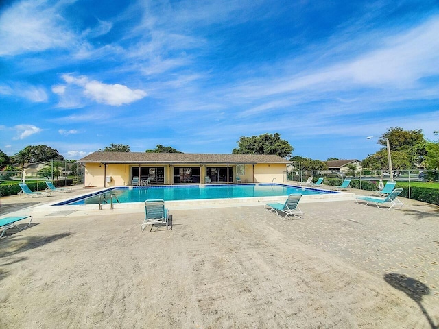 pool with a patio area and fence