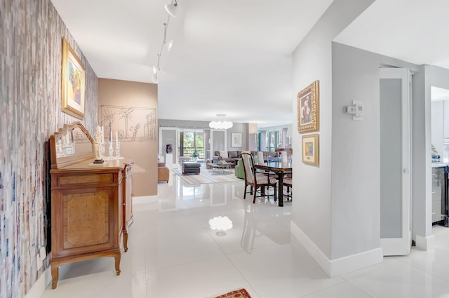 hallway with light tile patterned floors, rail lighting, and baseboards