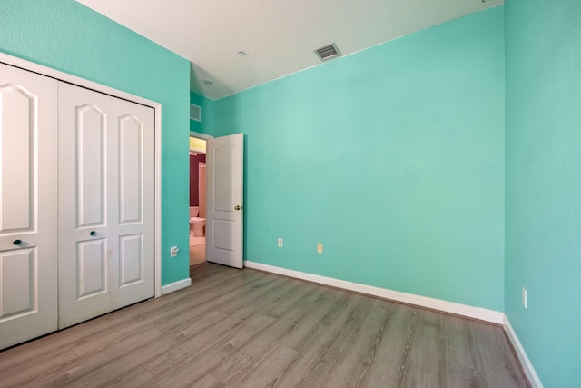 unfurnished bedroom with light wood-type flooring, a closet, visible vents, and baseboards