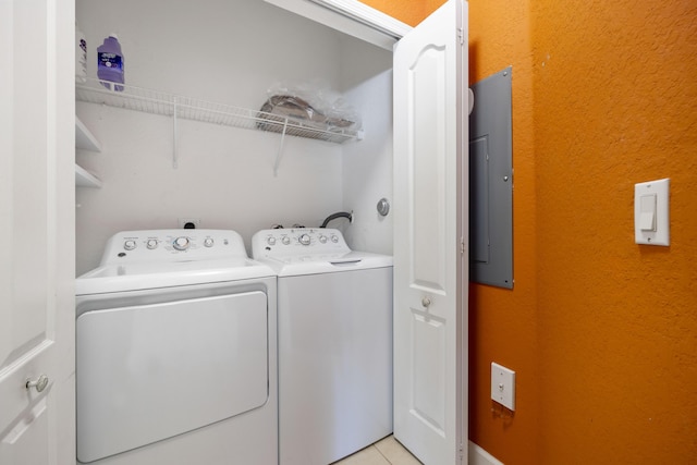 clothes washing area with laundry area, electric panel, light tile patterned floors, and washing machine and clothes dryer