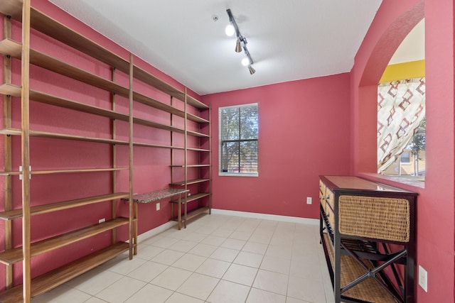 home office featuring baseboards, track lighting, arched walkways, and tile patterned floors