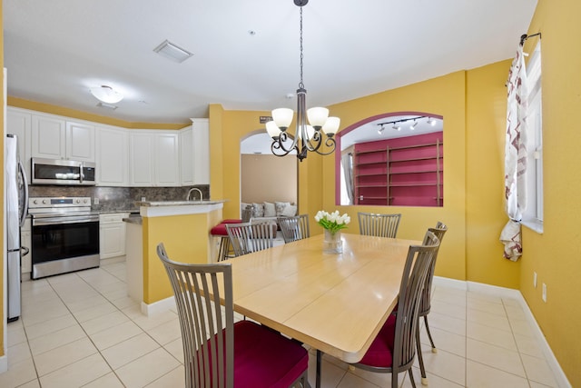 dining room with light tile patterned flooring, a notable chandelier, visible vents, and baseboards