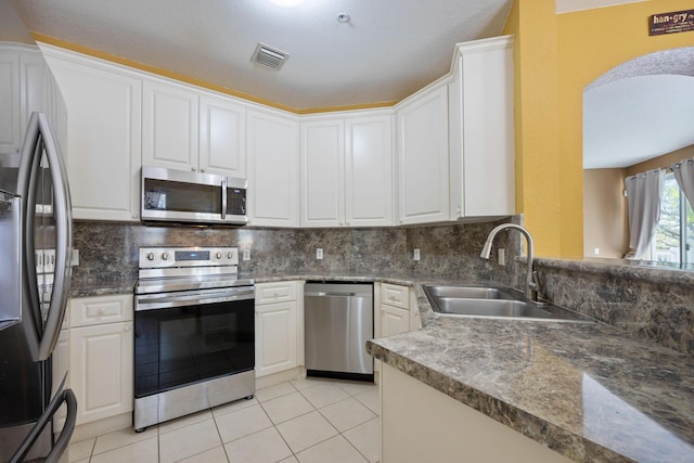 kitchen featuring stainless steel appliances, a sink, visible vents, white cabinetry, and backsplash