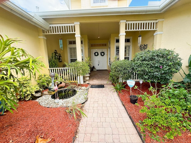 entrance to property with covered porch and stucco siding