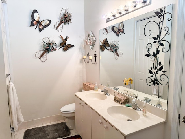 bathroom with a sink, toilet, double vanity, and tile patterned flooring