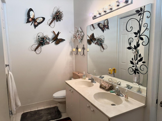 bathroom with a sink, toilet, double vanity, and tile patterned flooring