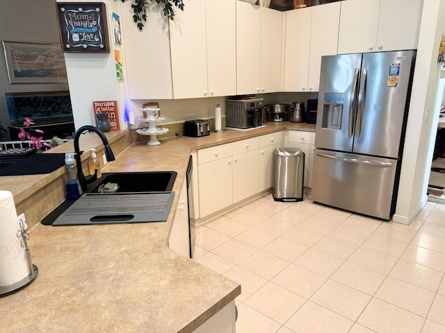 kitchen with a sink, light countertops, black dishwasher, white cabinetry, and stainless steel fridge