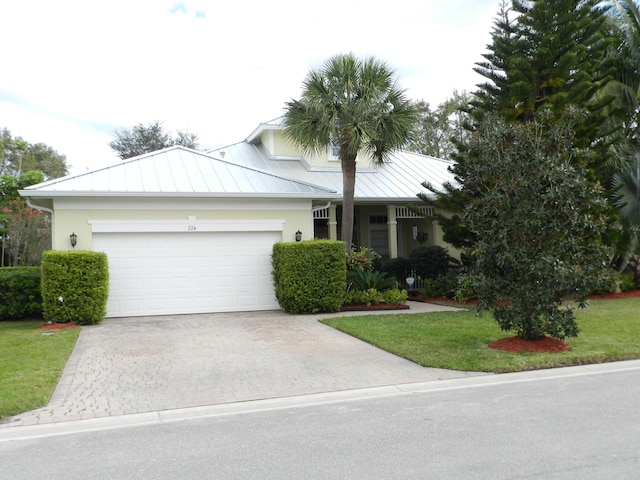 ranch-style house with a standing seam roof, an attached garage, stucco siding, decorative driveway, and metal roof