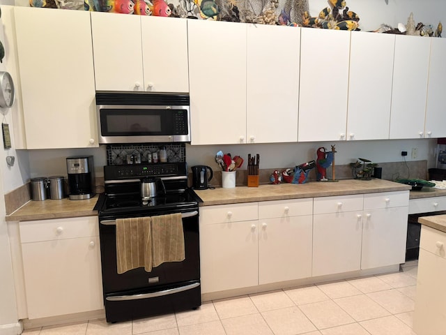 224 NW Pleasant Grove Way, Port Saint Lucie, FL 34986 - kitchen featuring stainless steel microwave, light countertops, light tile patterned floors, black electric range oven, and white cabinetry