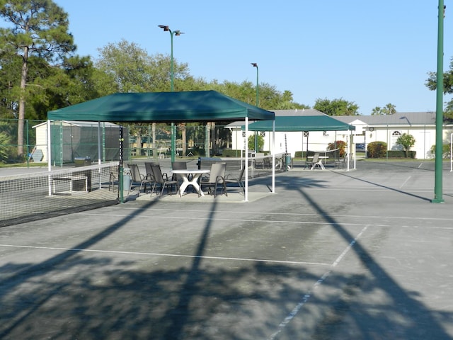 view of community with a tennis court and fence