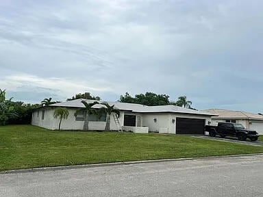 ranch-style house with a garage, driveway, and a front lawn