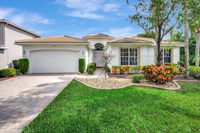 mediterranean / spanish home with a garage, a tiled roof, decorative driveway, and stucco siding