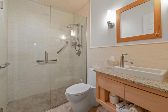 bathroom with tiled shower, toilet, a wainscoted wall, vanity, and tile walls