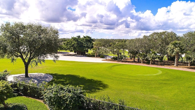 view of property's community with view of golf course, fence, and a lawn