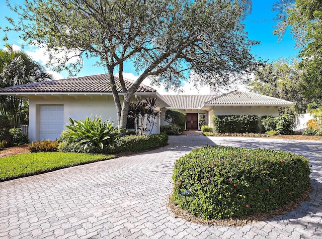 single story home with a garage, a tiled roof, decorative driveway, and stucco siding