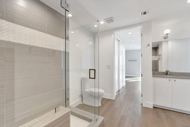 full bath featuring a stall shower, visible vents, vanity, and wood finished floors