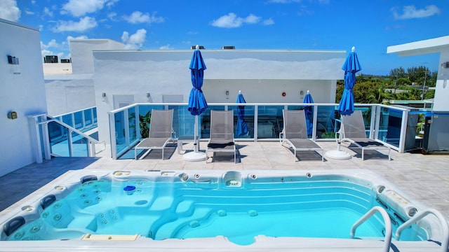 view of pool with hot tub deck surround and a patio