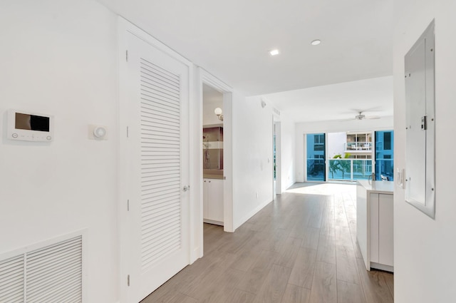 corridor featuring visible vents, light wood-style flooring, and baseboards