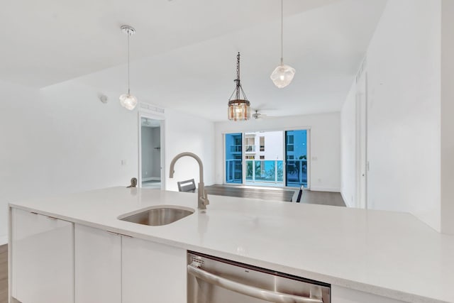 kitchen with pendant lighting, light countertops, open floor plan, a sink, and dishwasher