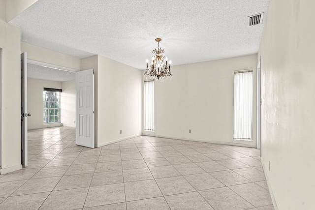 unfurnished room featuring light tile patterned floors, visible vents, and a notable chandelier