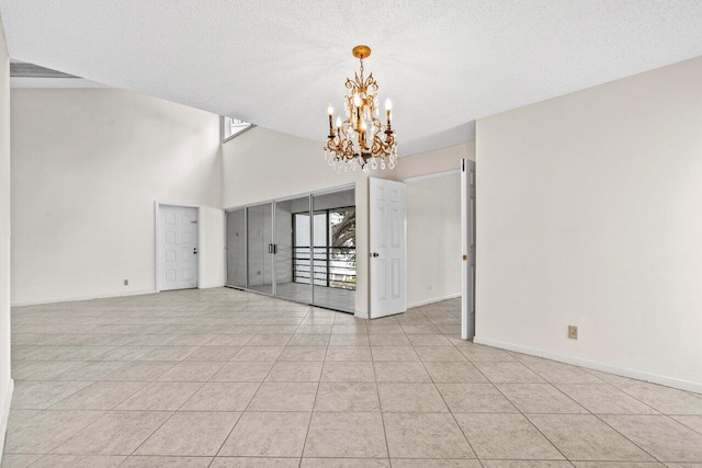 empty room featuring light tile patterned floors, a textured ceiling, baseboards, and a notable chandelier