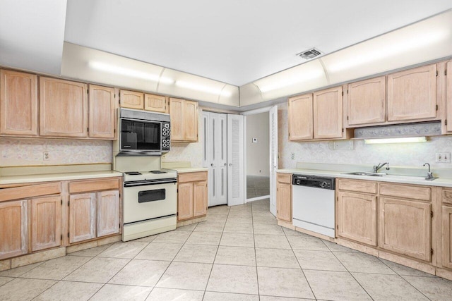 kitchen featuring white appliances, light countertops, a sink, and light brown cabinetry