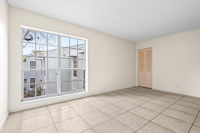 tiled spare room with baseboards and a textured ceiling