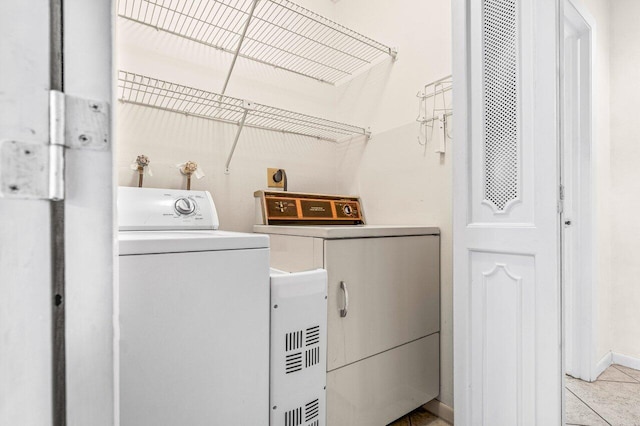 laundry room featuring tile patterned flooring, laundry area, baseboards, and separate washer and dryer