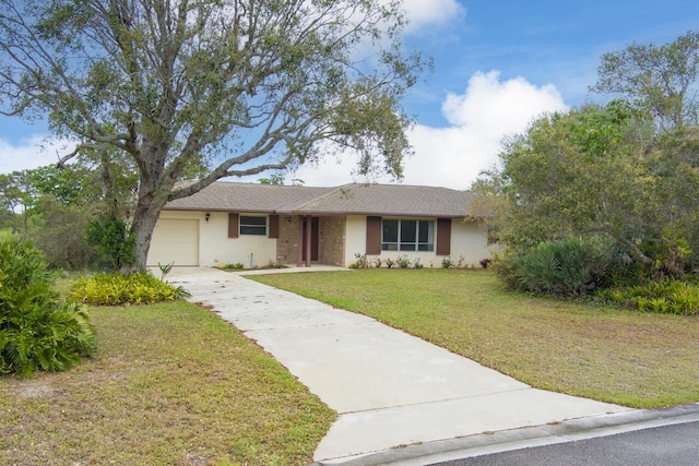 ranch-style home featuring a front yard, concrete driveway, and an attached garage