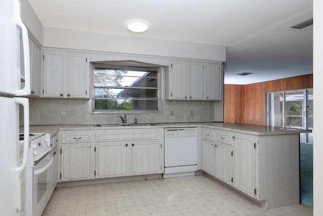 kitchen featuring a peninsula, white appliances, a sink, backsplash, and light floors