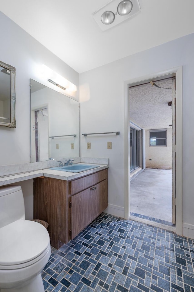 bathroom featuring toilet, baseboards, and vanity