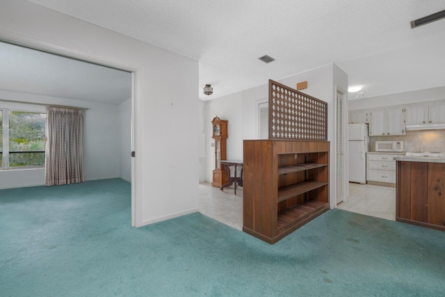 living room featuring a textured ceiling, visible vents, and light colored carpet