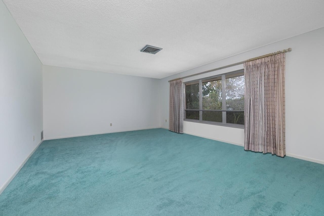 empty room featuring carpet, visible vents, and a textured ceiling