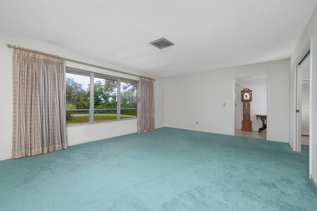 carpeted empty room featuring visible vents and a textured ceiling