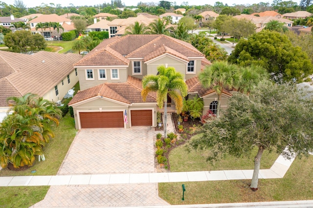 view of front of property featuring a residential view, decorative driveway, a tiled roof, and stucco siding